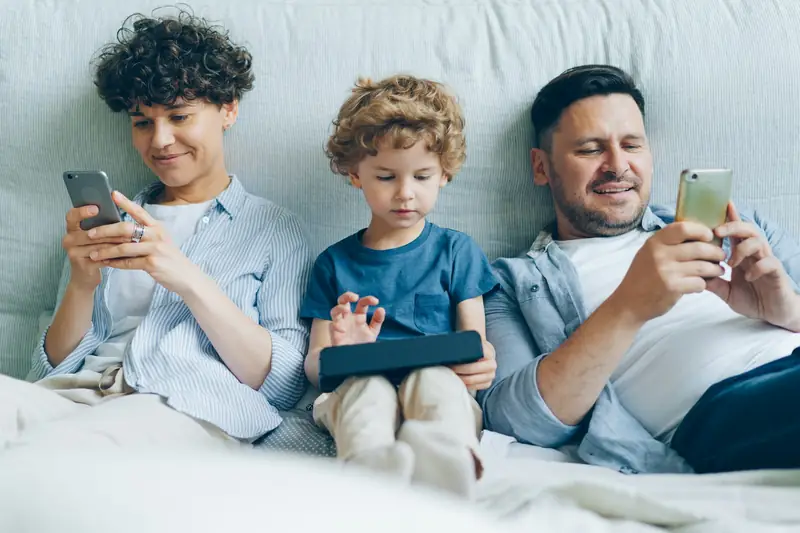 Família no sofá usando celulares
